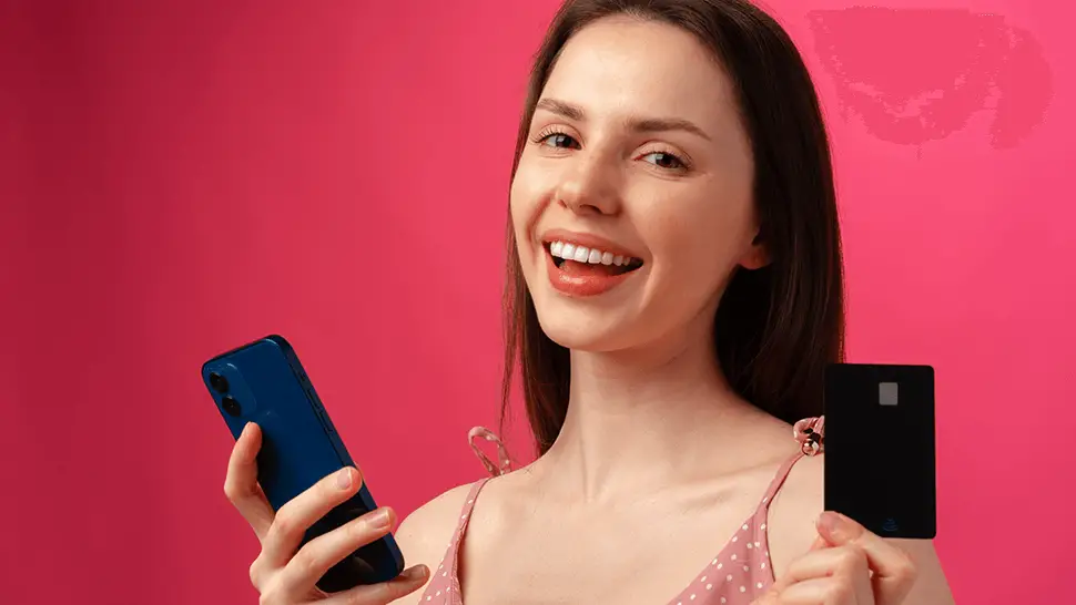 smiling young woman holding smartphone credit card How To Build a Good Credit Score Fast